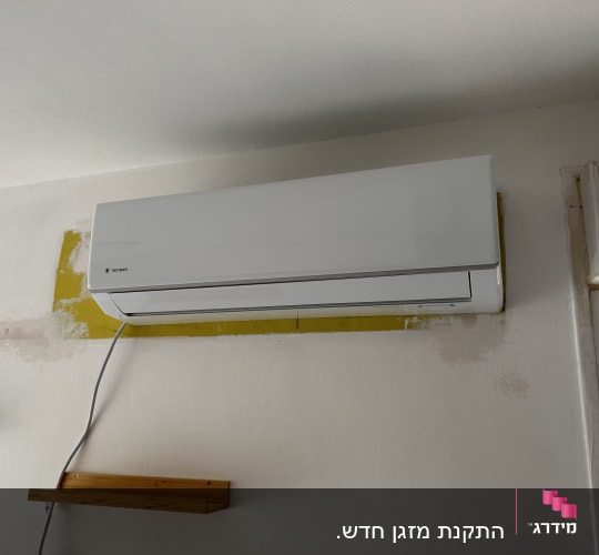 יחידת מיזוג אוויר מותקנת על קיר עם כבל חשמל
